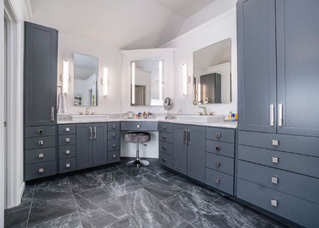 Walk in closet with grey cabinets and marble tiles